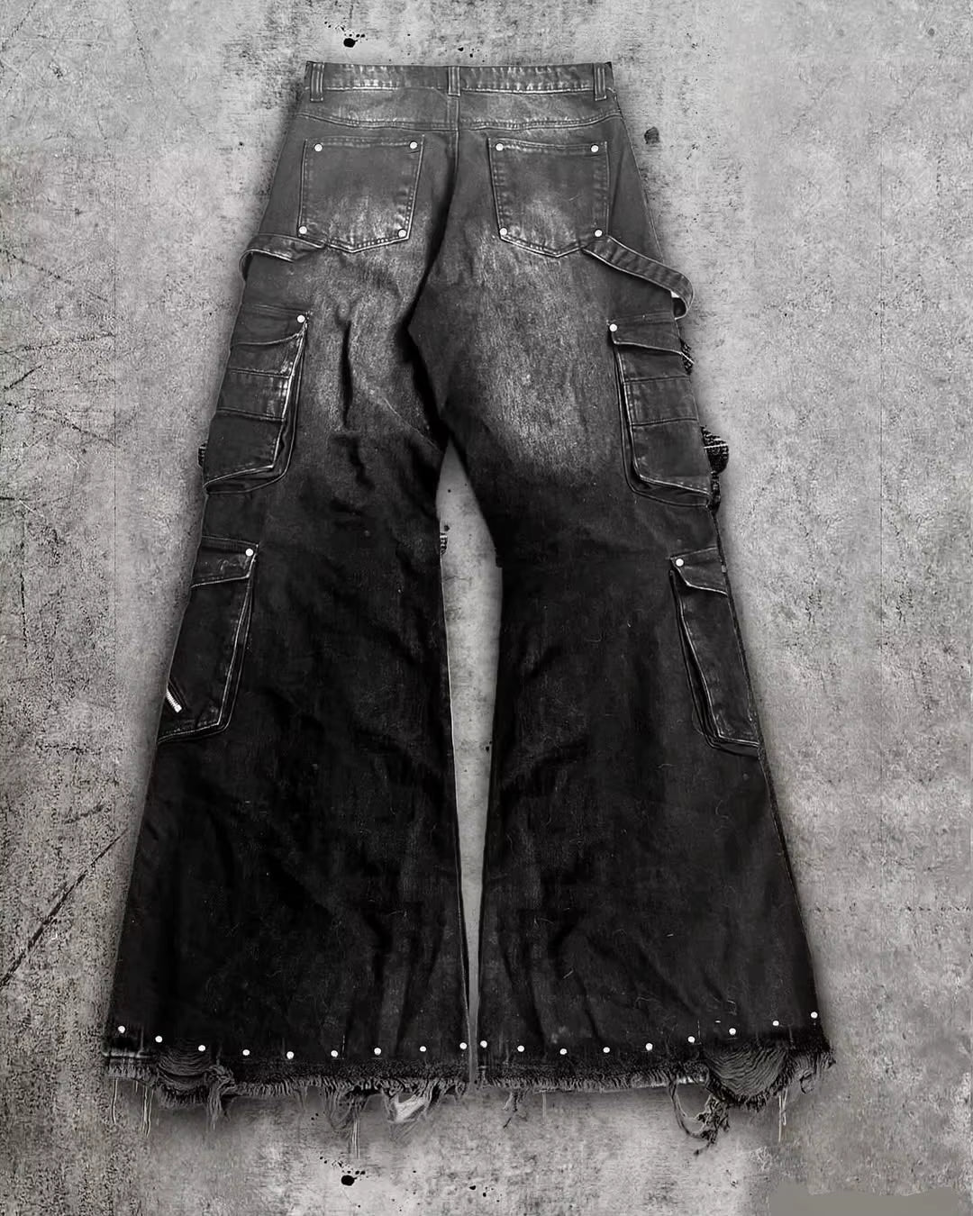 Pantalones cargo goth punk negros multibolsillos acampanados con correas cremalleras tachuelas bordes deshilachados streetwear alternativo por detras
