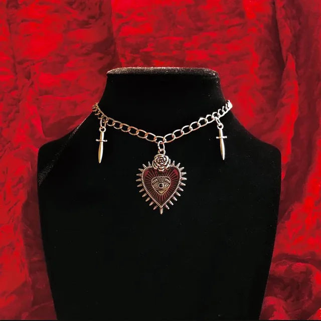 Collar gótico metálico con cuatro variantes: corazón, murciélago con ataúd, murciélago con cruz, joyería dark.
Esta imagen muestra la variante con corazón.