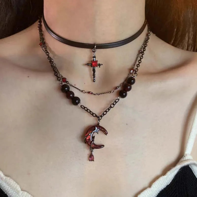 Modelo vistiendo un collar gótico con colgante de cruz metálica, luna sangrienta de cristal rojo, cuentas estilo unisex alternativo 