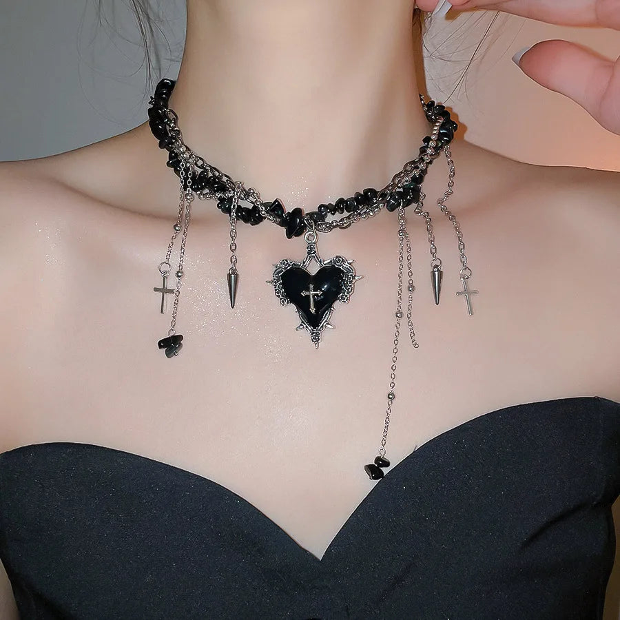 Colgante gótico de corazón con cruces, cadenas y pedrería, disponible en negro y rojo, esta imagen muestra el negro llevado por una chica. Joyería romántica dark
