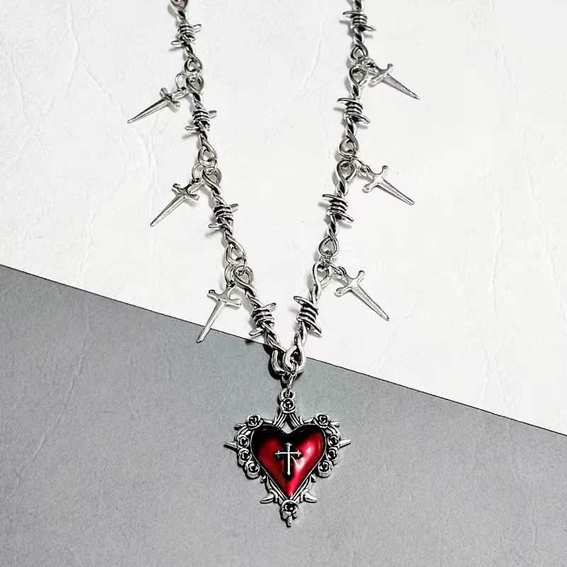 Imagen de cerca de un Collar gótico punk con corazón envuelto en espinas y cadena de alambre con púas decorada con múltiples dagas colgantes, joyería extrema
