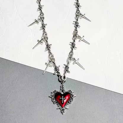 Imagen de cerca de un Collar gótico punk con corazón envuelto en espinas y cadena de alambre con púas decorada con múltiples dagas colgantes, joyería extrema
