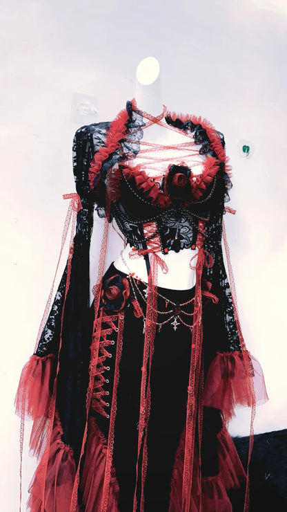 lateral izquierdo de un conjuto vestido completo separado, con top corto, mangas largas y falda larga, de colores rojo y negro con tiras rojas de tela