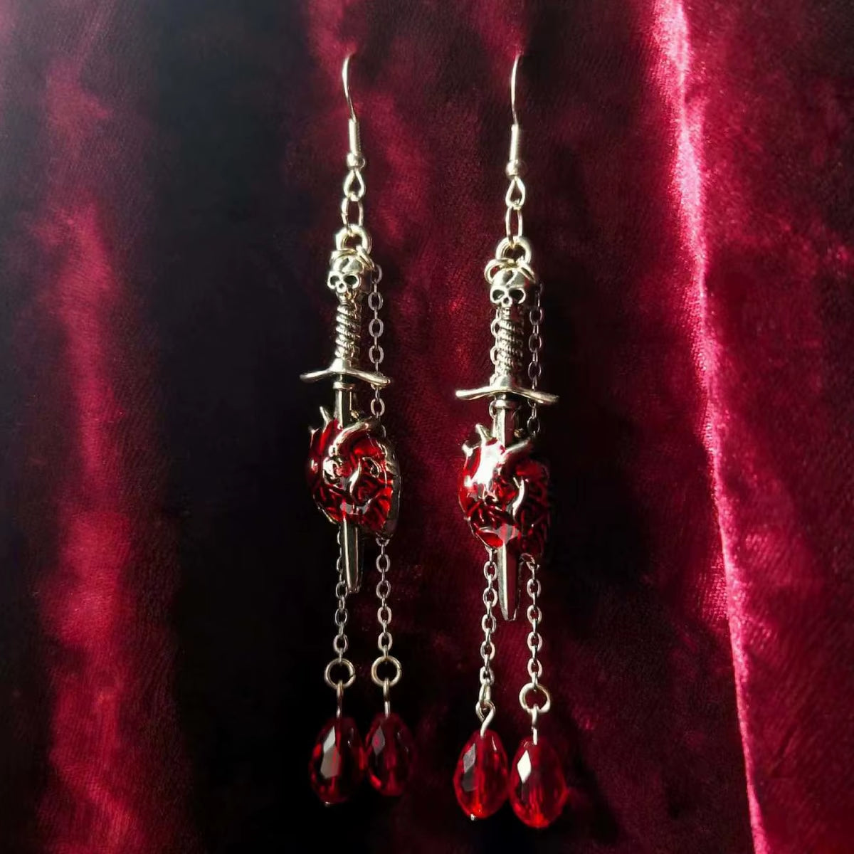 Pendientes góticos de vampiro con corazón y pedrería roja sangrienta, disponibles con corazón simple o atravesado por puñal, joyería dark.
Esta imagen muestra la version con el corazón detallado atravesado por un puñal.
