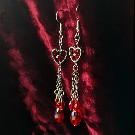 Pendientes góticos de vampiro con corazón y pedrería roja sangrienta, disponibles con corazón simple o atravesado por puñal, joyería dark.
Esta imagen muestra la version con el corazón simple.
