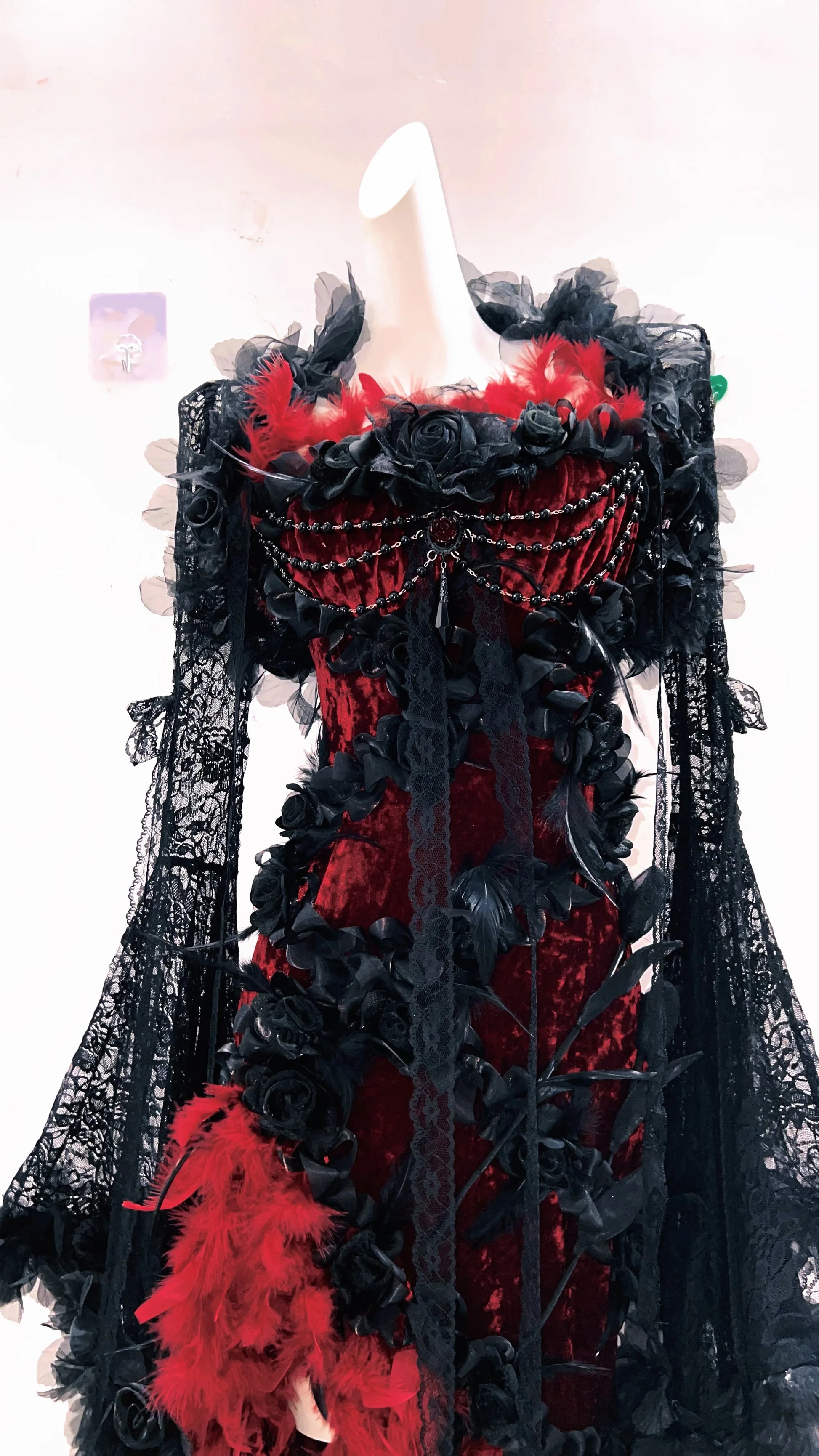 Imagen de cerca de un vestido formal Red Feather de 2 piezas con estética de plumas rojas, mangas largas de encaje vintage y rosas negras entrelazadas estilo gótico
