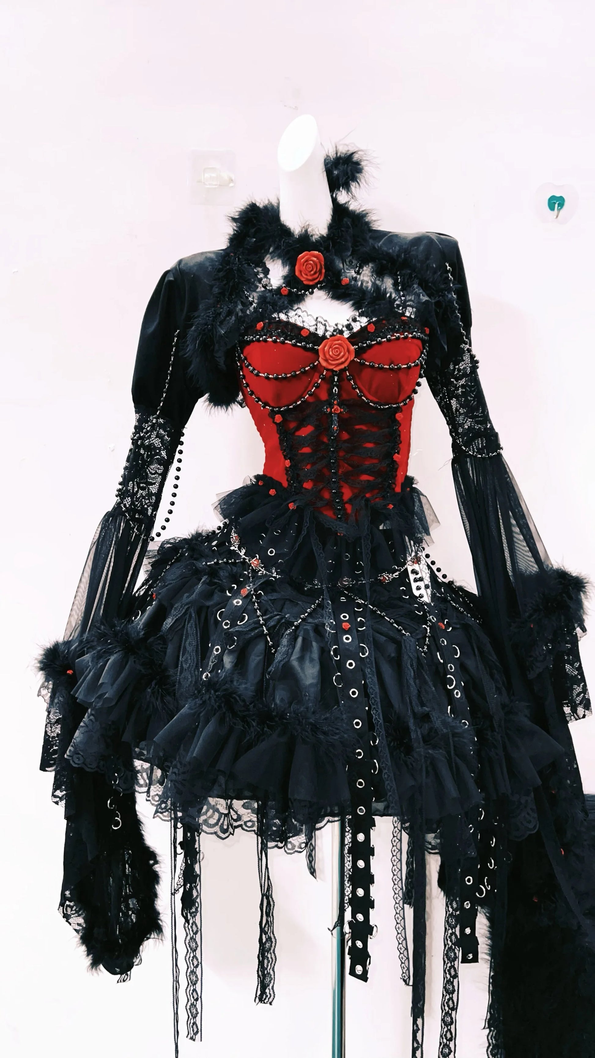 Vestido Gotico de color rojo y negro, con una falda y mangas largas. Tiene pelaje decorativo y detalles metalicos